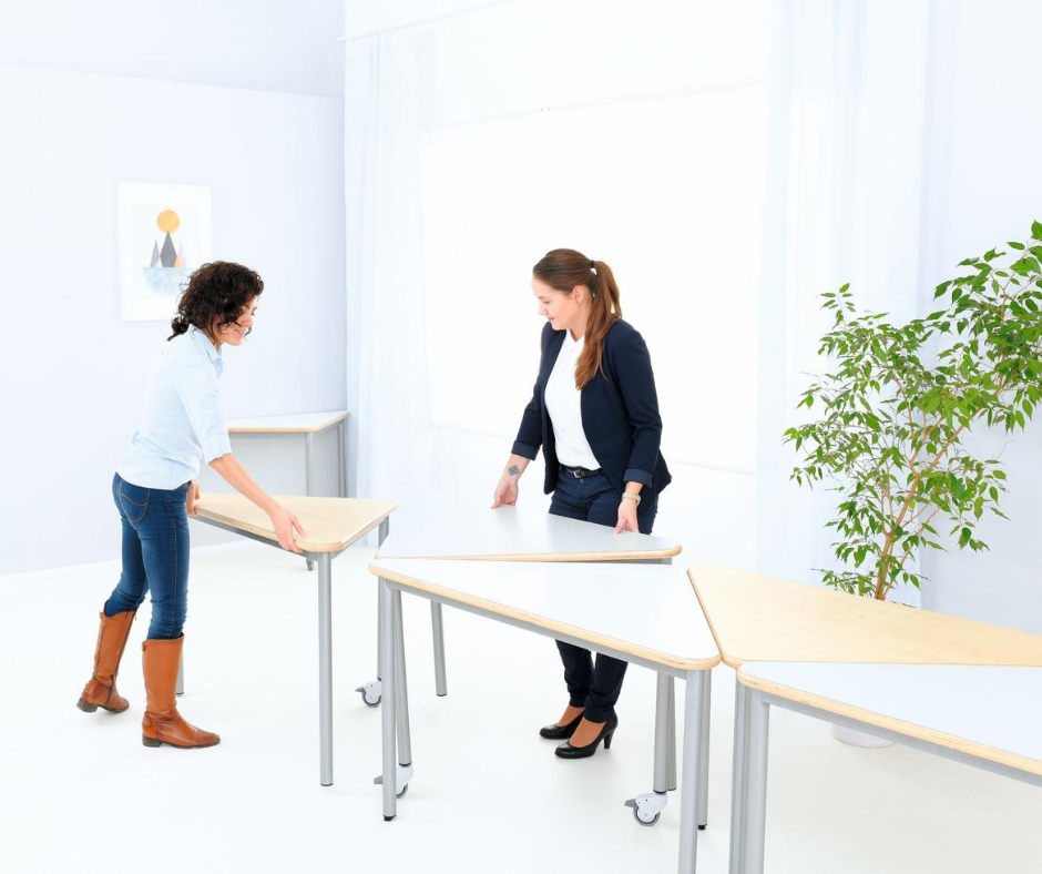 Twee juffen verschuiven tafels in de klas